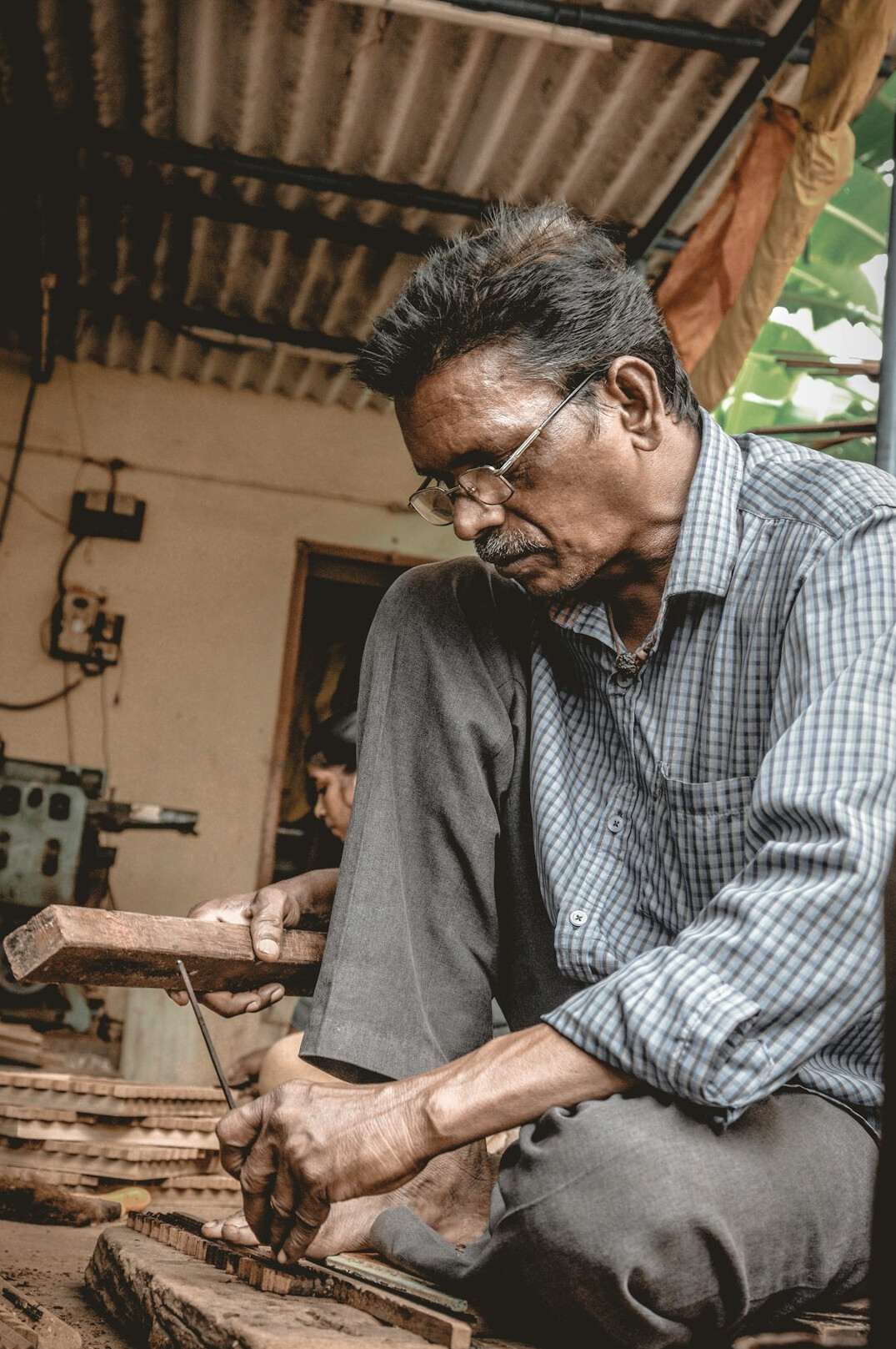 Elderly craftsman working with wood tools in a small workshop