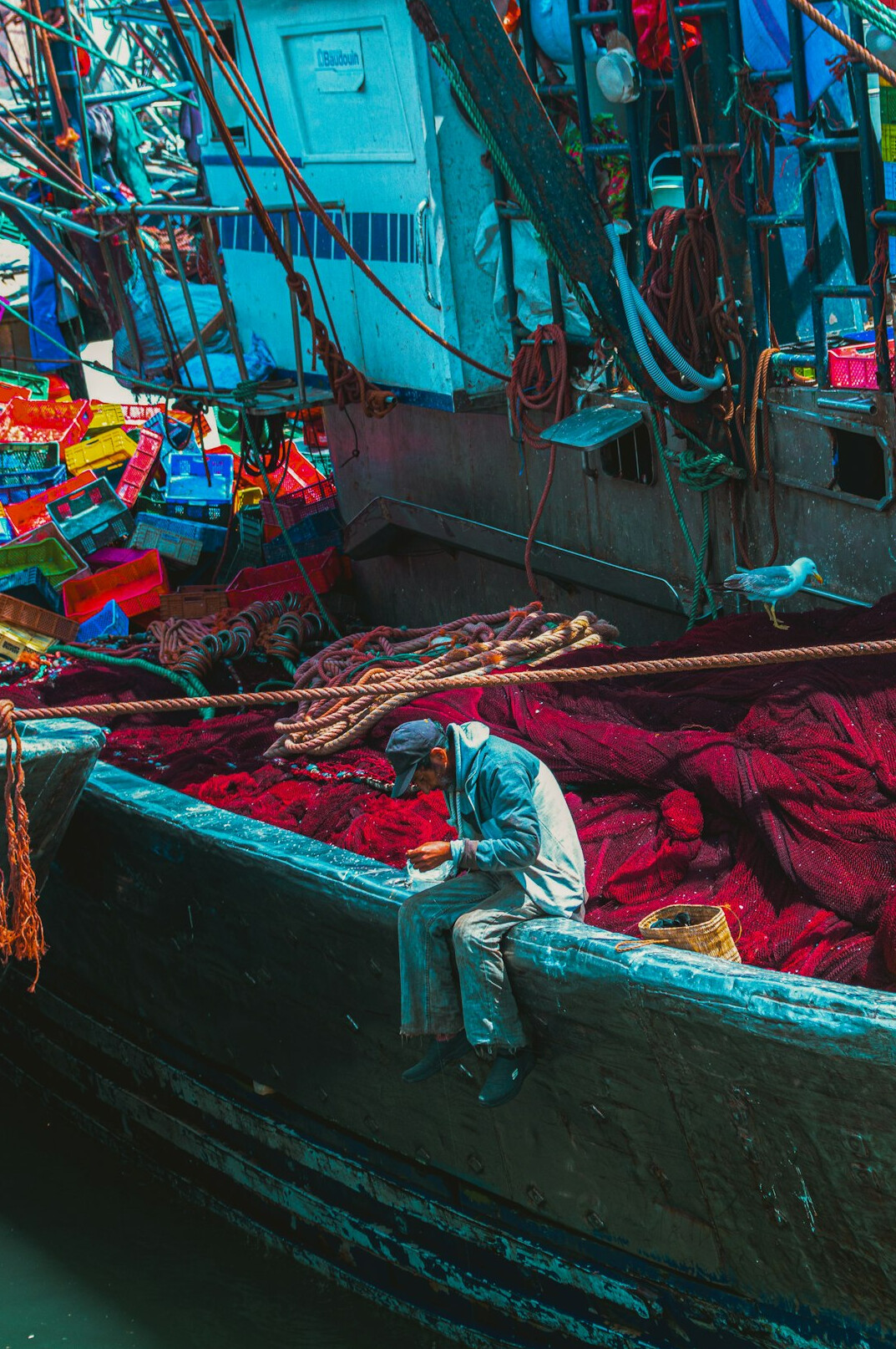 Fisherman mending nets on a boat at a coastal harbor